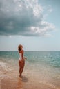 Beautiful girl in a white bodysuit walks along the shore of the azure sea