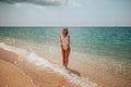 Beautiful girl in a white bodysuit walks along the shore of the azure sea Royalty Free Stock Photo