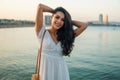 Beautiful girl in the white dress along the sea promenade.