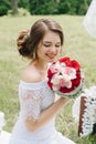 Beautiful girl in a white dress with a bouquet of flowers on nature in summer on a background of green leaves Royalty Free Stock Photo