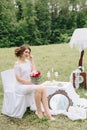 Beautiful girl in a white dress with a bouquet of flowers on nature in summer on a background of green leaves Royalty Free Stock Photo