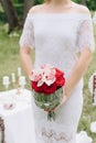 Beautiful girl in a white dress with a bouquet of flowers on nature in summer on a background of green leaves Royalty Free Stock Photo