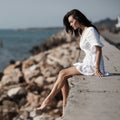 Beautiful woman in white summer dress sitting alone by the sea in summer Royalty Free Stock Photo