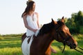 Beautiful girl in white dress sitting on horse