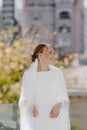 Beautiful girl in a white dress stands on the balcony looking at the city Royalty Free Stock Photo