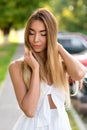 Beautiful girl in white dress in the summer city on the street. Close-up long hair, tanned skin, everyday makeup. Hands Royalty Free Stock Photo