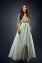 Beautiful Girl in white Long Chiffon Dress. Romantic Bride in Wedding Gown with Curly Long Hairstyle over Gray. Happy Smiling Royalty Free Stock Photo