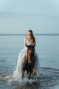 Beautiful girl in a white long dress riding a horse. Bride in the lake on horseback. Royalty Free Stock Photo