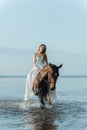 Beautiful girl in a white long dress riding a horse. Bride in the lake on horseback. Royalty Free Stock Photo