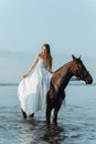 Beautiful girl in a white long dress riding a horse. Bride in the lake on horseback. Royalty Free Stock Photo