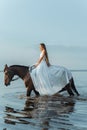 Beautiful girl in a white long dress riding a horse. Bride in the lake on horseback. Royalty Free Stock Photo