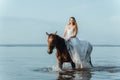 Beautiful girl in a white long dress riding a horse. Bride in the lake on horseback. Royalty Free Stock Photo