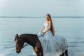 Beautiful girl in a white long dress riding a horse. Bride in the lake on horseback. Royalty Free Stock Photo