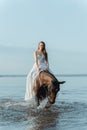 Beautiful girl in a white long dress riding a horse. Bride in the lake on horseback. Royalty Free Stock Photo