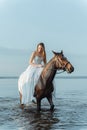 Beautiful girl in a white long dress riding a horse. Bride in the lake on horseback. Royalty Free Stock Photo