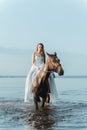 Beautiful girl in a white long dress riding a horse. Bride in the lake on horseback. Royalty Free Stock Photo