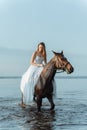 Beautiful girl in a white long dress riding a horse. Bride in the lake on horseback. Royalty Free Stock Photo