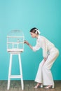 beautiful girl in white outfit looking parrot in cage Royalty Free Stock Photo