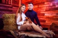 Beautiful girl in white shirt and guy in black sweater with small dog on the couch with hay in the barn or in the hayloft with Royalty Free Stock Photo