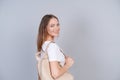 A beautiful girl in white t-shirt with backpack on her back, student smiles