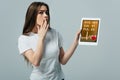 Beautiful girl in white t-shirt showing digital tablet with cardiological app isolated on grey