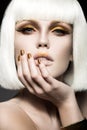 Beautiful girl in a white wig, with gold makeup and nails. Celebratory image. Beauty face. Royalty Free Stock Photo