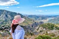 Beautiful girl with a wide hat, standing with her back on a background of green mountains Royalty Free Stock Photo