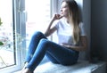 Woman on a white windowsill on the skin. The woman thinks about dreams Royalty Free Stock Photo