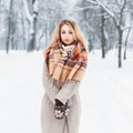 Beautiful girl with a winter coat and scarf stands in the park