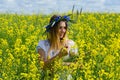 Beautiful girl in wreath of cornflowers on flowering rapeseed field