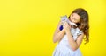Beautiful girl on a yellow background holds in her arms and hugs a little cute kitten. Royalty Free Stock Photo