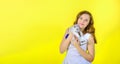 Beautiful girl on a yellow background holds in her arms and hugs a little cute kitten Royalty Free Stock Photo