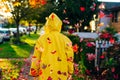 Beautiful girl in the yellow raincoat walking outdoors in autumn. Young woman enjoying autumn weather Royalty Free Stock Photo
