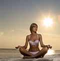 Beautiful girl yoga on the beach at sunset