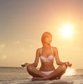 Beautiful girl yoga on the beach at sunset