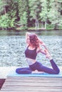 Beautiful girl in a yoga pose on the lake. Eka Pada Rajakapotasana . One Legged King Pigeon Pose . The concept of appeasement,