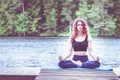 Beautiful girl in a yoga pose on the lake. Lotus position , Padmasana. The concept of appeasement, healthy lifestyle. Space for