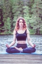 Beautiful girl in a yoga pose on the lake. Lotus position , Padmasana. The concept of appeasement, healthy lifestyle