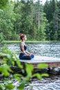 Beautiful girl in a yoga pose on the lake. Lotus position , Padmasana. The concept of appeasement, healthy lifestyle. Panoramic
