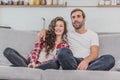 Beautiful girl and a young man sitting on the couch and watch TV. People relax on the couch.Young man in glasses and Royalty Free Stock Photo