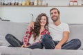 Beautiful girl and a young man sitting on the couch and watch TV. People relax on the couch.Young man in glasses and Royalty Free Stock Photo