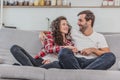 Beautiful girl and a young man sitting on the couch and watch TV. People relax on the couch.Young man in glasses and Royalty Free Stock Photo