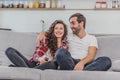 Beautiful girl and a young man sitting on the couch and watch TV. People relax on the couch.Young man in glasses and Royalty Free Stock Photo