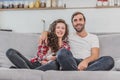 Beautiful girl and a young man sitting on the couch and watch TV. People relax on the couch.Young man in glasses and Royalty Free Stock Photo