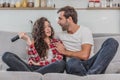 Beautiful girl and a young man sitting on the couch and watch TV. People relax on the couch.Young man in glasses and Royalty Free Stock Photo