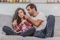 Beautiful girl and a young man sitting on the couch and watch TV. People relax on the couch.Young man in glasses and Royalty Free Stock Photo