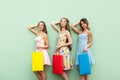 Beautiful girls in dress, standing in front of green background . Hands crossed under head, holding her colorful bags, relaxed aft Royalty Free Stock Photo