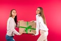 Beautiful girls posing with big gift box on a pink background. Holiday concept