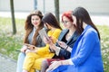 Beautiful girls sit and chat with gadgets on the bench. The concept of the Internet, social networks, study and lifestyle Royalty Free Stock Photo