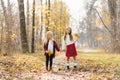 Beautiful girls sit in the yellow leaves of the autumn Park. Two sisters holding hands and walking in the woods. The concept of a Royalty Free Stock Photo